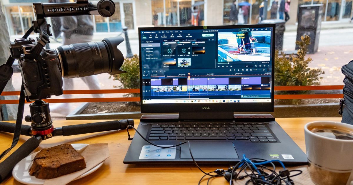 Câmara em tripé ao lado de um portátil com uma timeline de edição de vídeo aberta, num café
